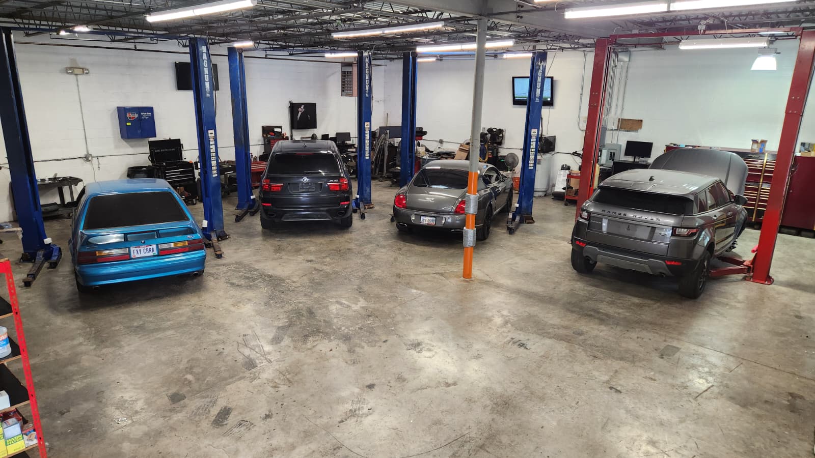 Multiple vehicles on lifts inside the shop — rear view