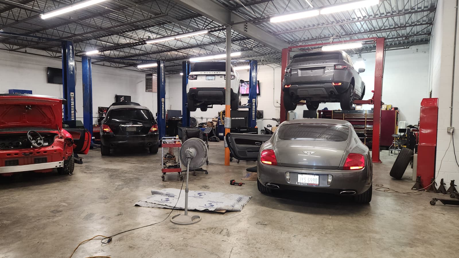 Bentley and Range Rover on lifts with technicians at work