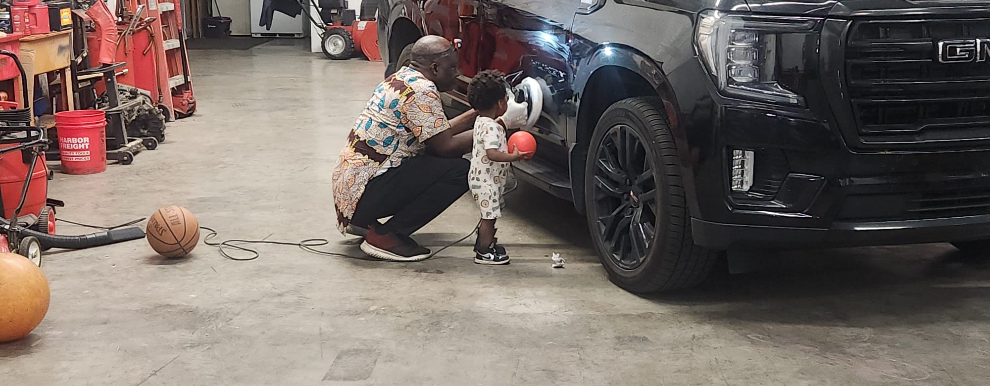 Technician polishing a black GMC Yukon in the shop